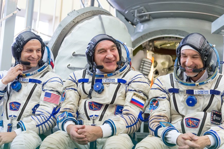 1920px-Soyuz_MS-11_backup_crew_in_front_of_the_Soyuz_spacecraft_mockup-870x579